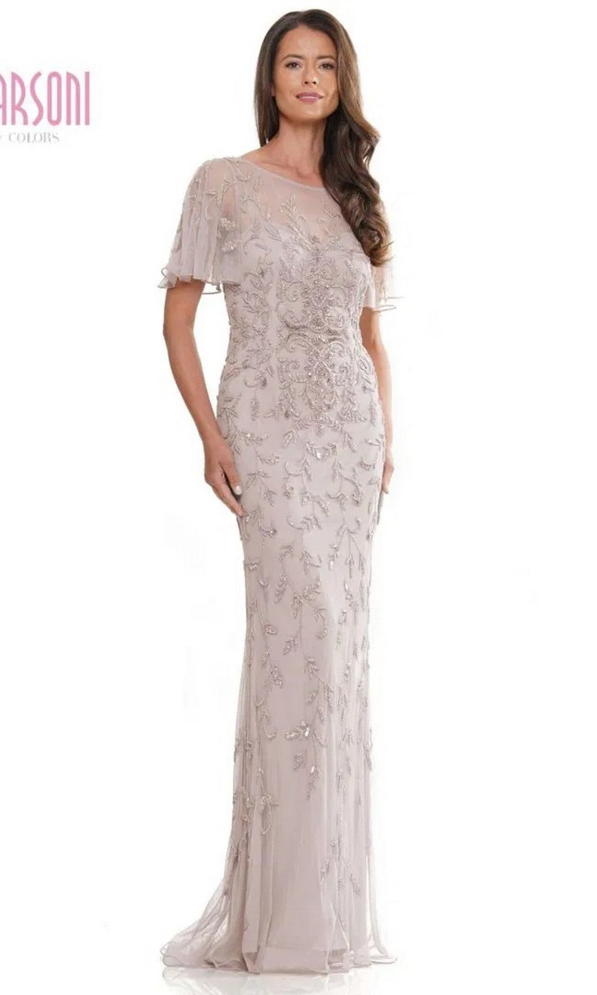 A woman models the Marsoni MV1281 long formal dress in champagne, featuring a floor-length skirt, sheer short sleeves, an illusion sweetheart neckline, and intricate bead embroidery, against a plain white backdrop.